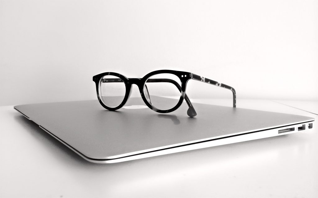 Constant Counsel Apple computer with eyeglasses on top